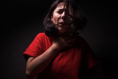 Portrait of woman with neckache against black background