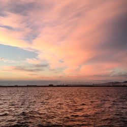 Scenic view of sea against cloudy sky at sunset