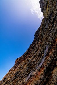 Low angle view of rocky mountains against blue sky