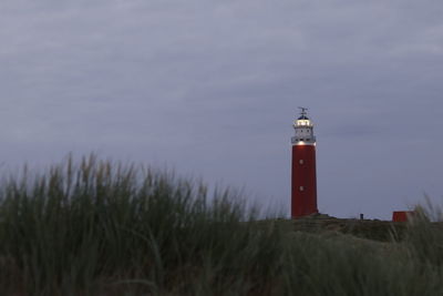Lighthouse at coastline against sky during dusk