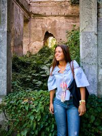 Smiling young woman standing against old ruins