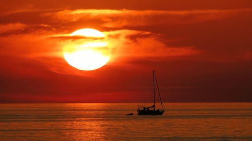 Silhouette of ship in sea during sunset