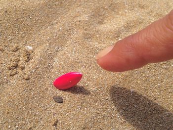 Close-up of hand holding heart shape on sand