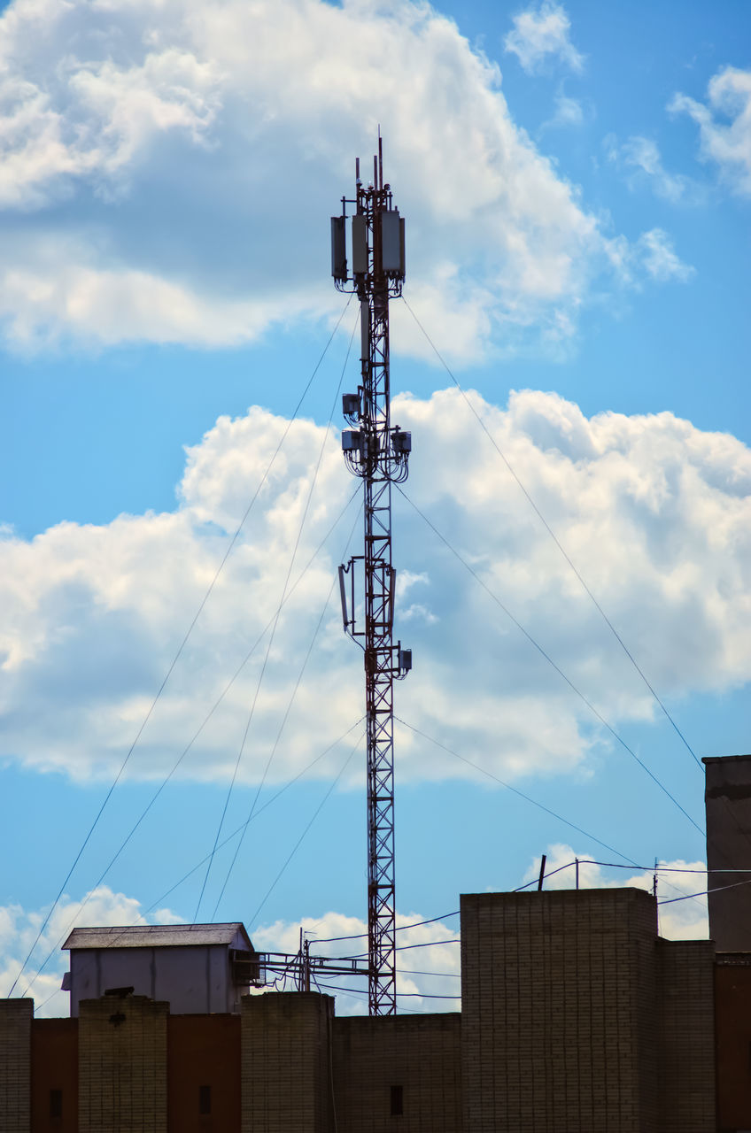 LOW ANGLE VIEW OF COMMUNICATIONS TOWER BY BUILDINGS AGAINST SKY