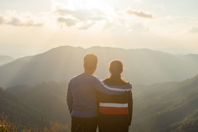 Rear view of friends looking at landscape during sunset