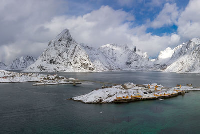 Scenic view of sea by snow covered mountain against sky