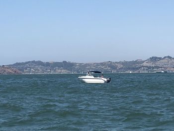 Boat sailing in sea against clear sky