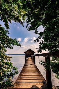 View of wooden pier leading towards sea against sky