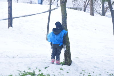 Rear view of person on snowcapped field during winter