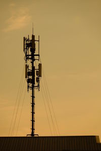 Low angle view of silhouette communications tower against sky during sunset