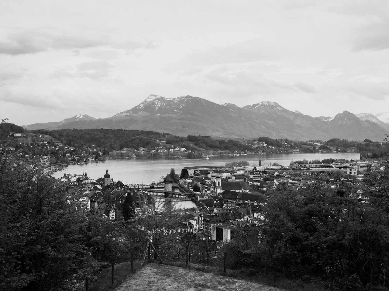 mountain, mountain range, architecture, built structure, building exterior, sky, house, town, landscape, tree, scenics, water, cloud - sky, residential structure, tranquil scene, tranquility, nature, hill, beauty in nature, residential building