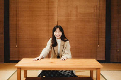 Portrait of a smiling young woman sitting on table