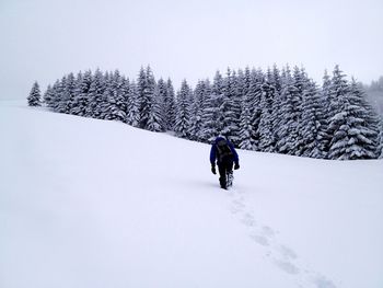 Man hiking on snowy field against sky