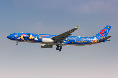 Low angle view of airplane flying against clear blue sky