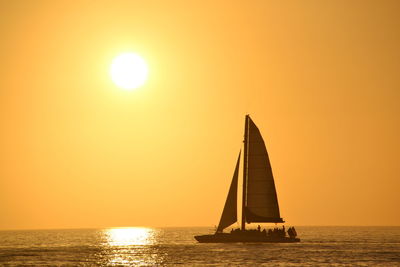 Sailboat sailing on sea against clear sky during sunset