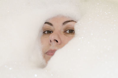 Portrait of woman amidst soap sud in bathtub