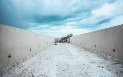 Elevated walkway against cloudy sky