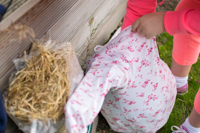 Low section of girl making scarecrow