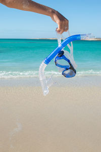 Low section of man on beach against sky