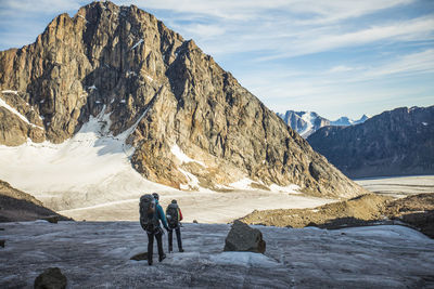 Rear view of people on rocks in mountains against sky