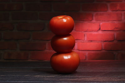 Close-up of tomatoes on table against brick wall