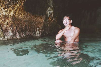 Smiling shirtless man in sea