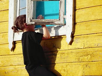 Rear view of woman standing against wall