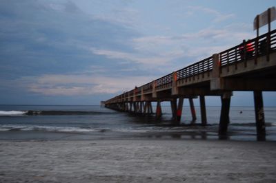 Pier on sea against cloudy sky