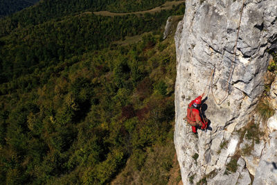 Aerial view of mountain rescuer rappelling on a rocky wall hanging on a rope