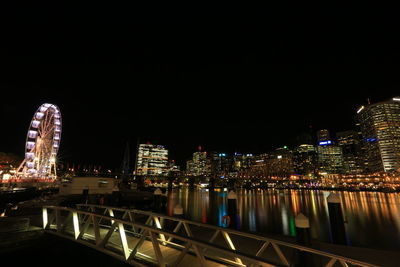 Illuminated buildings by city against sky at night