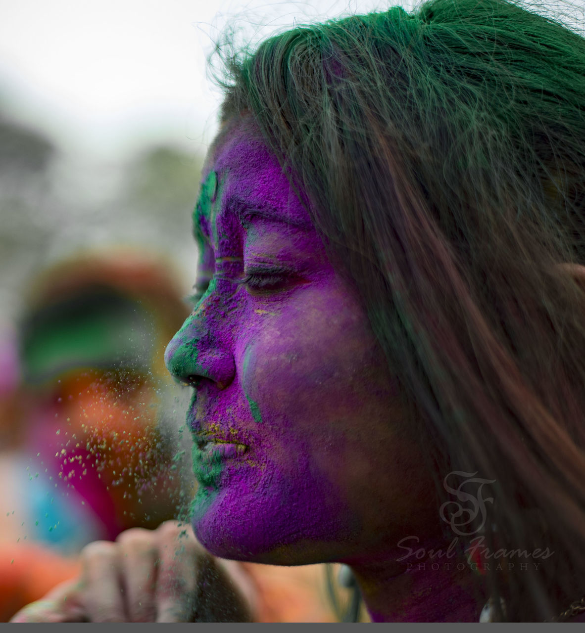 CLOSE-UP OF YOUNG WOMAN WITH MULTI COLORED HAIR IN MOUTH