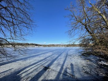 Snow covered landscape against clear blue sky