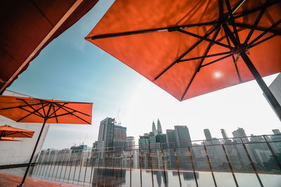 Red umbrellas on the roof top pool deck against the city skyline