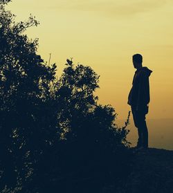 Silhouette man standing on field against sky during sunset
