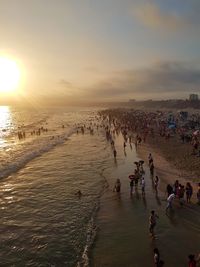 High angle view of people at beach against sky during sunset