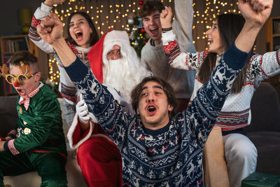 Group of fans watching a sporting event sitting on the sofa in their living room