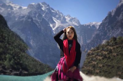 Portrait of smiling young woman standing on mountain against clear sky