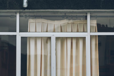 Detail of a window with old beige curtains.