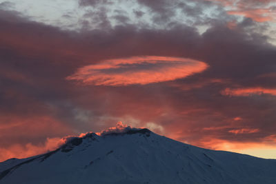 Scenic view of snowcapped mountain against cloudy sky during sunset