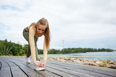 Full length of young woman exercising on lake