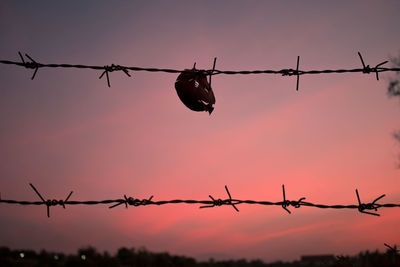 Silhouette of barbed wire against sky during sunset