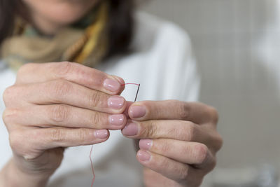 Cropped image of woman threading sewing needle