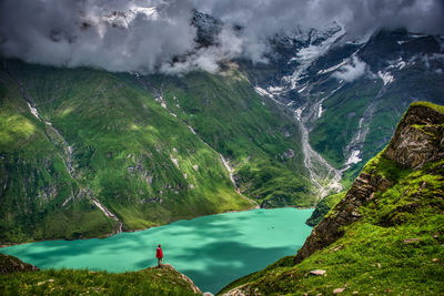 Person standing on mountain against lake