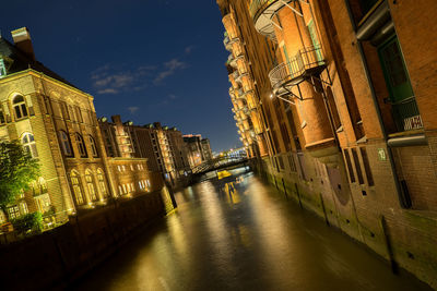 Canal amidst illuminated city against sky at night