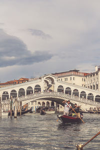 People on boats in canal against sky