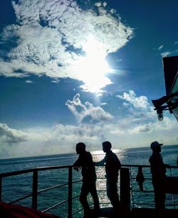 Silhouette people looking at sea against sky