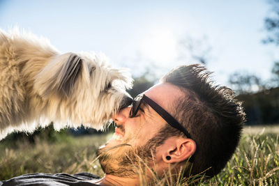 Close-up of man playing with dog on grassy field