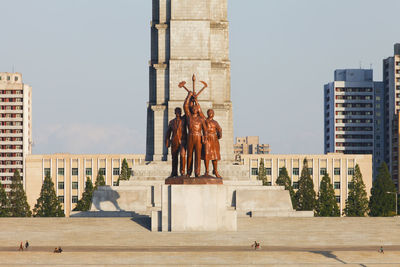 Statue in city against sky