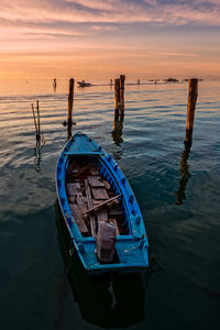 Boat moored in sea against sky during sunset