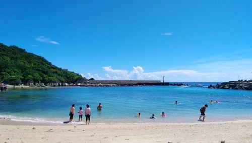 People at beach against blue sky